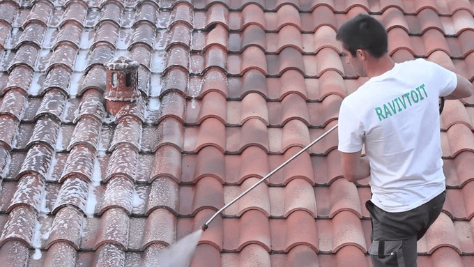 Application de produit anti-mousse sur toiture.